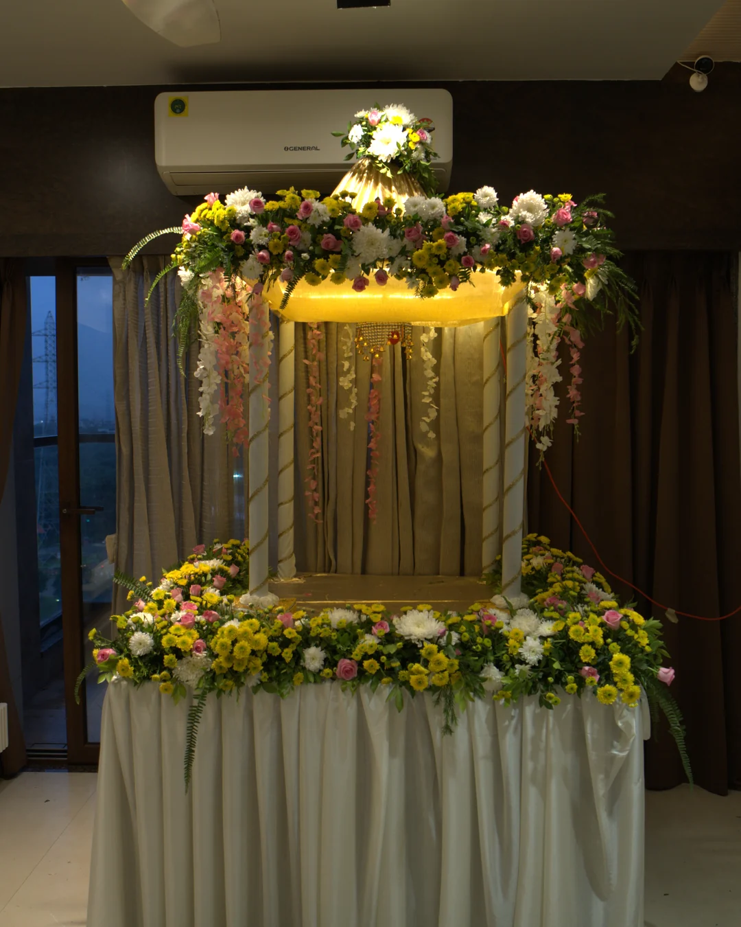 Golden two-tier canopy mandap with cascading flowers and warm uplight