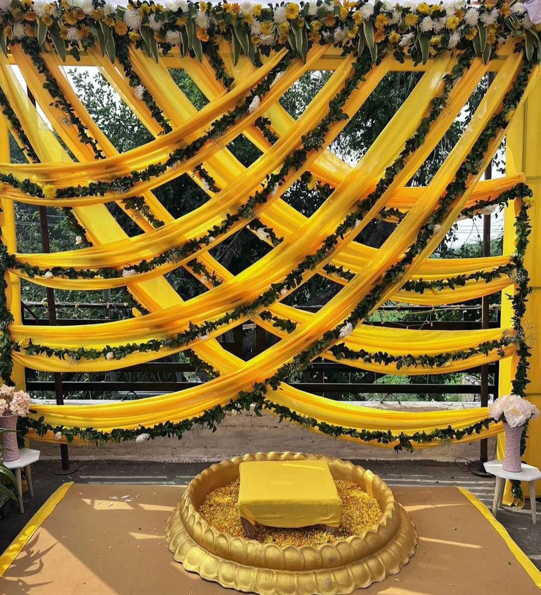 Haldi ceremony stage with yellow drapes and floral garlands